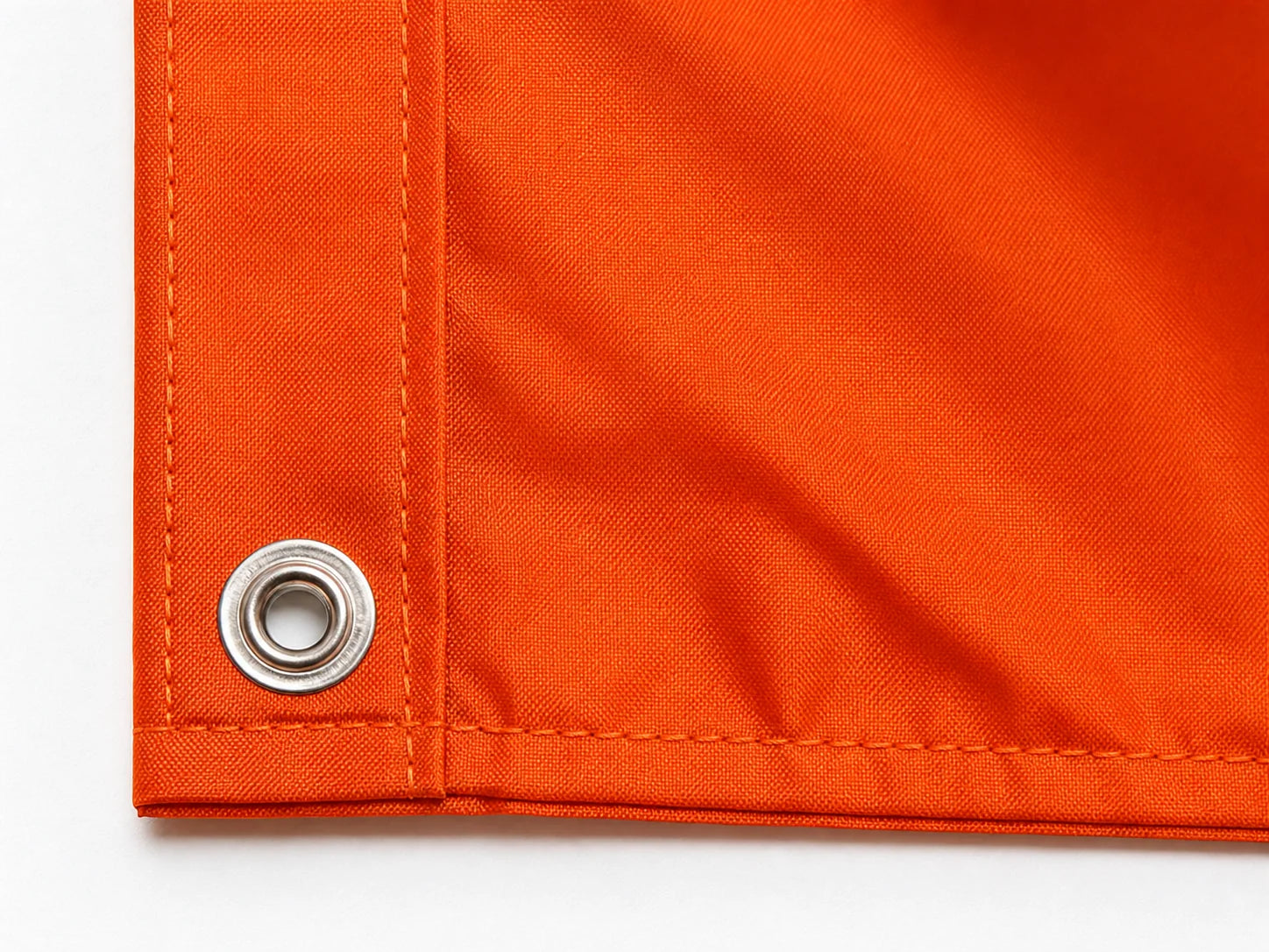 Close-up of the lower metal grommet and reinforced hem on an orange custom flag