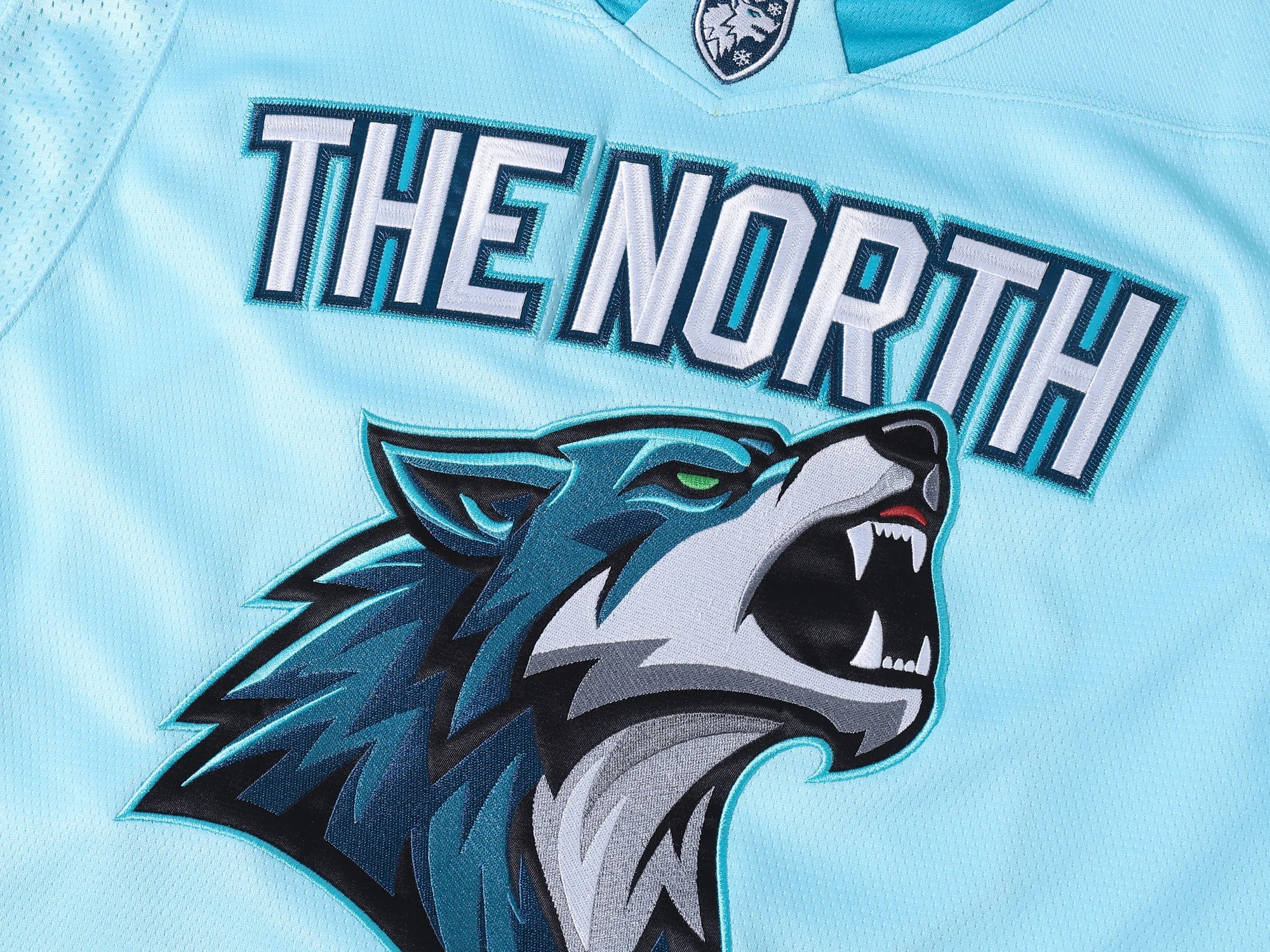 Close-up of THE NORTH wolf embroidery on a light blue HUINA hockey jersey